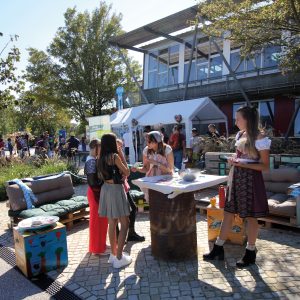 Zwei Mitarbeiterinnen vom Jugendzentrum Kirchheim informieren an einem Stand auf der Landesgartenschau drei Mädchen über die Präventionskampagne "Sichere Wiesn".