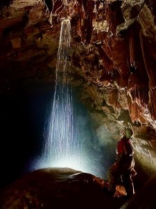 Mann in einer Höhle vor einem Wasserfall