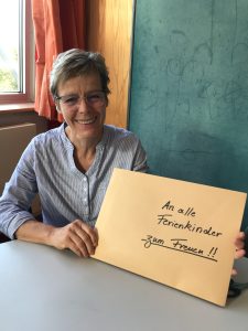 Pädagogin hält einen großen Briefumschlag mit den Worten "An alle Ferienkinder zum Freuen"